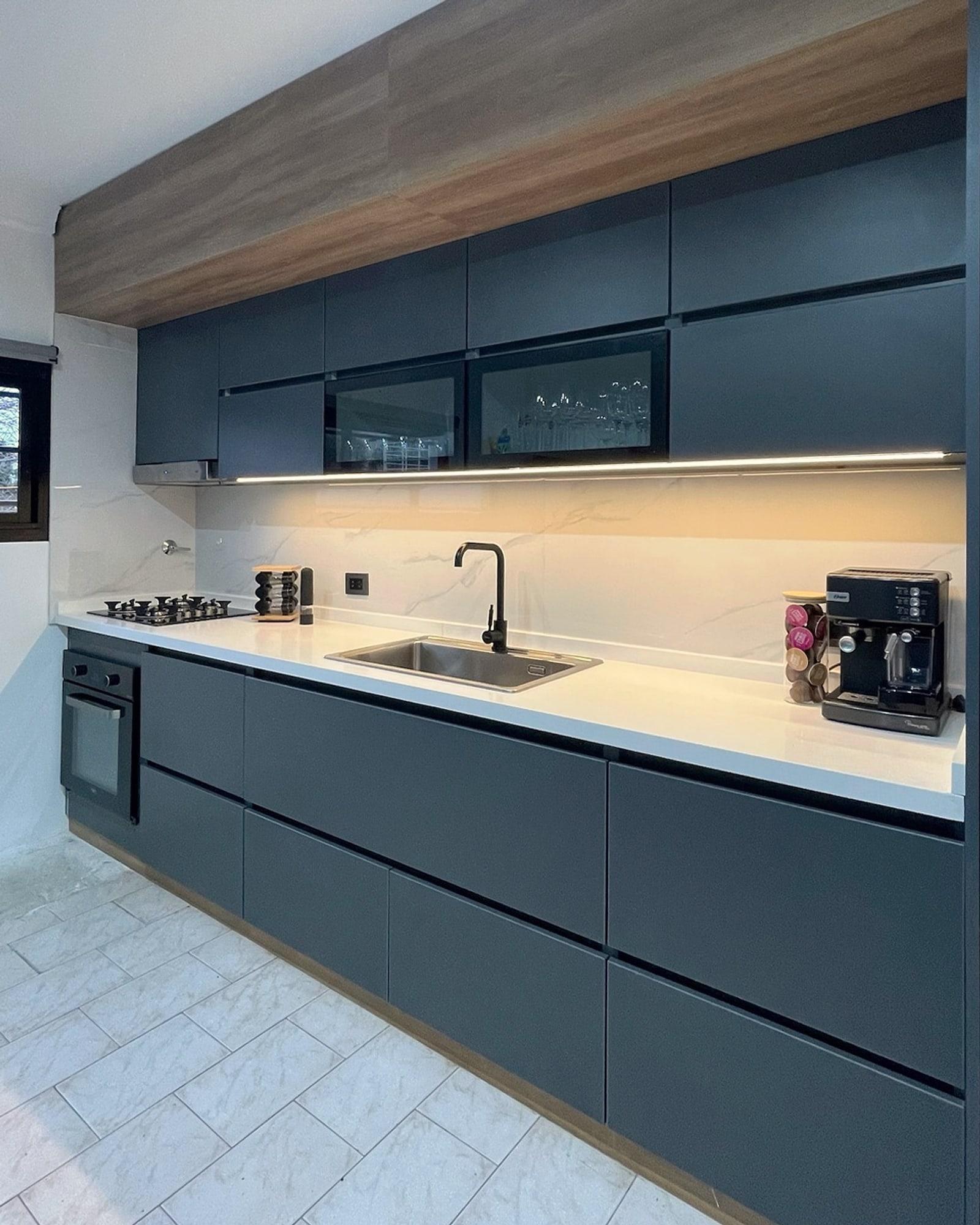 Cocina integral en laca azul, mesada blanca y frente de madera