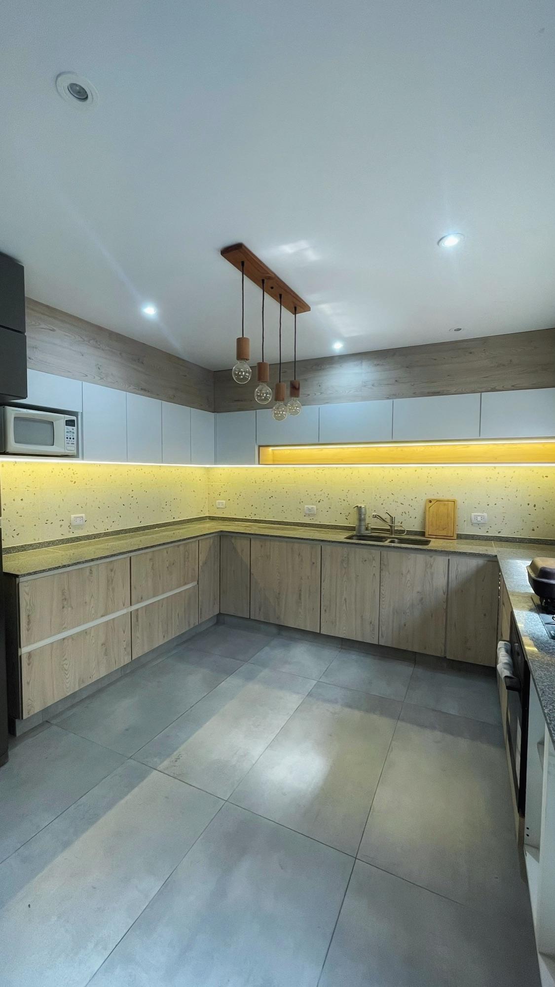 Cocina en U con bajo mesada de roble y alacenas blancas