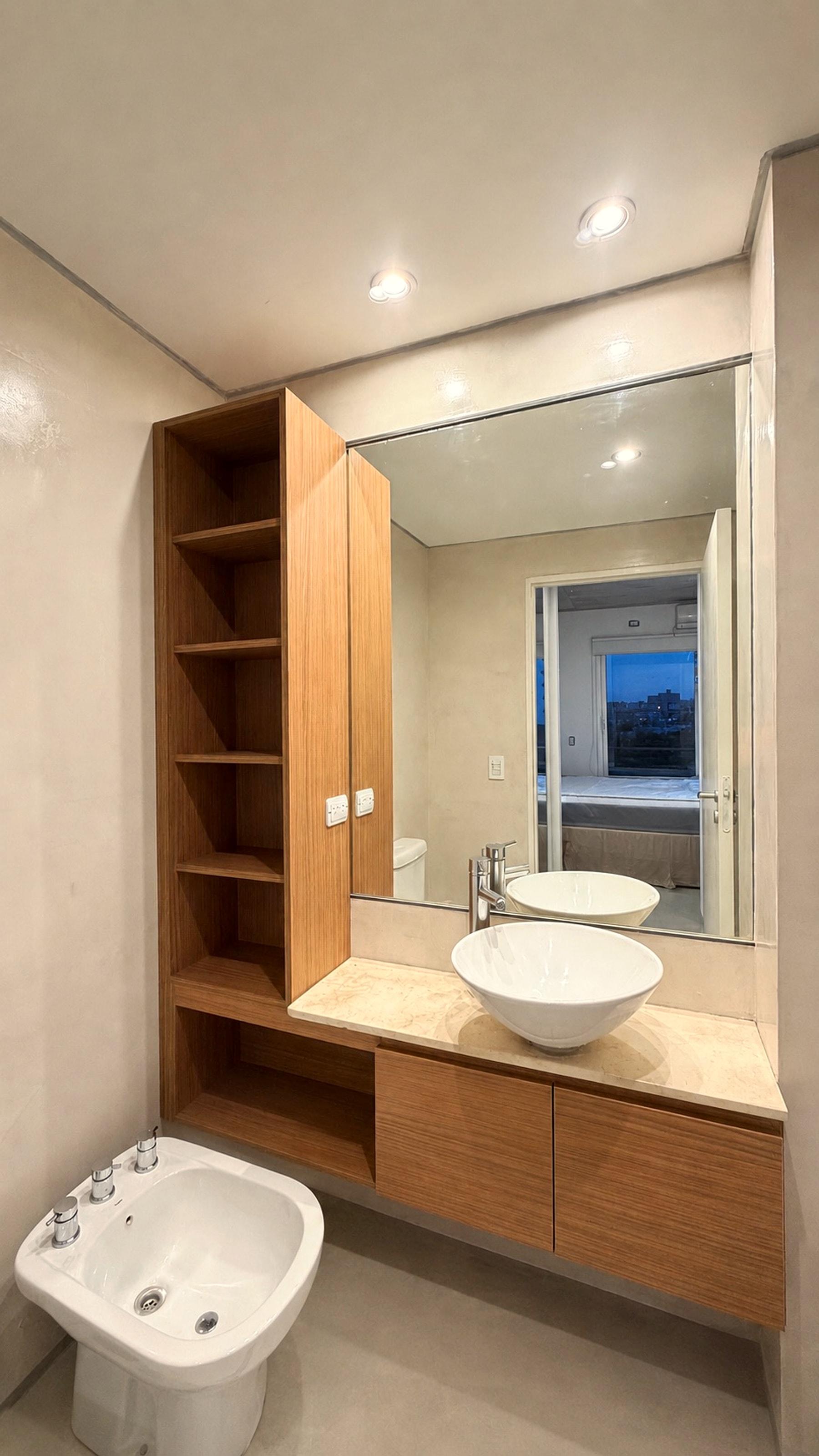 Mueble bajo mesada en madera clara con bacha sobrepuesta y torre de estantes abiertos