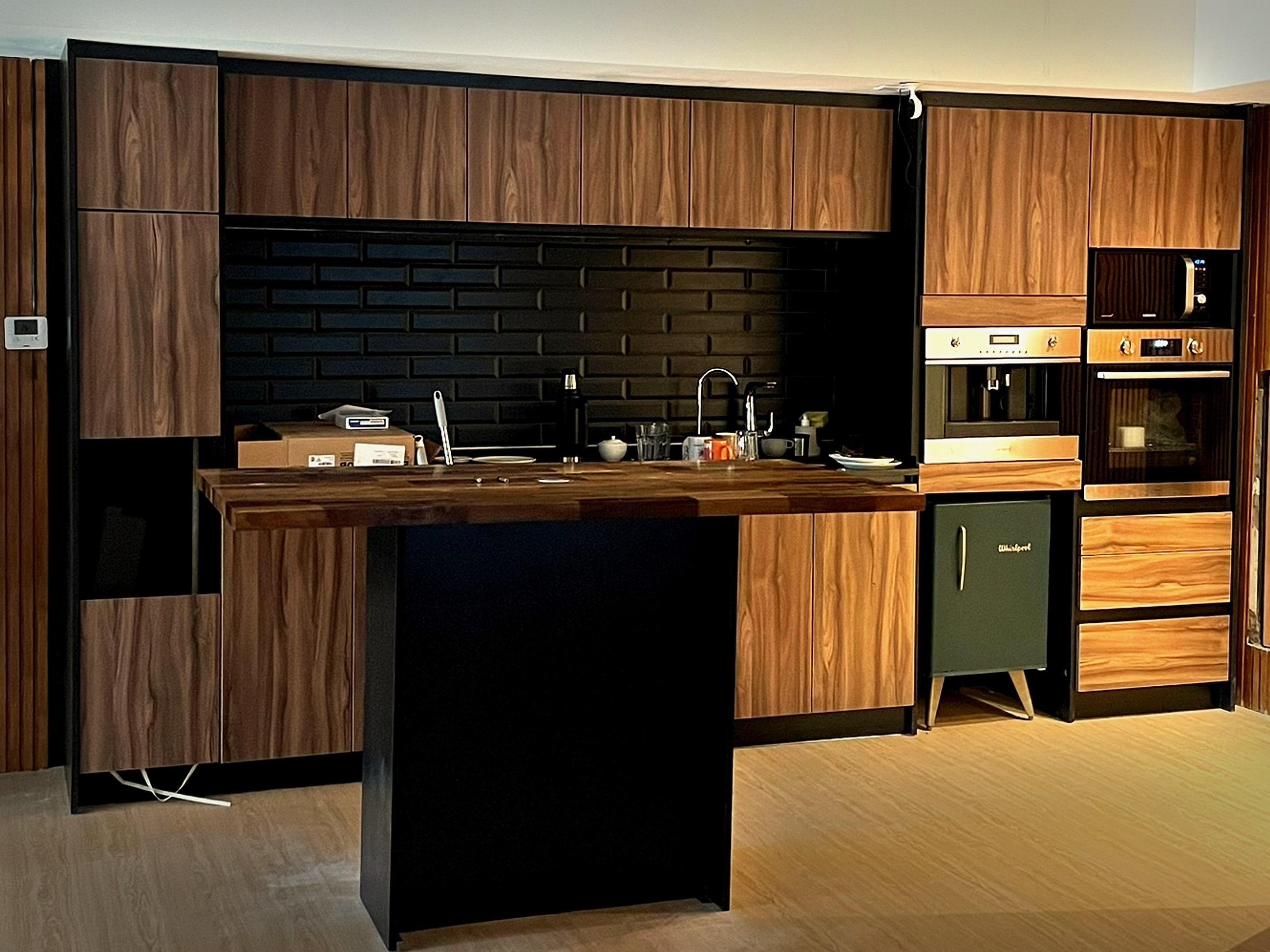 Cocina de oficina en madera, con isla y torre de electrodomésticos