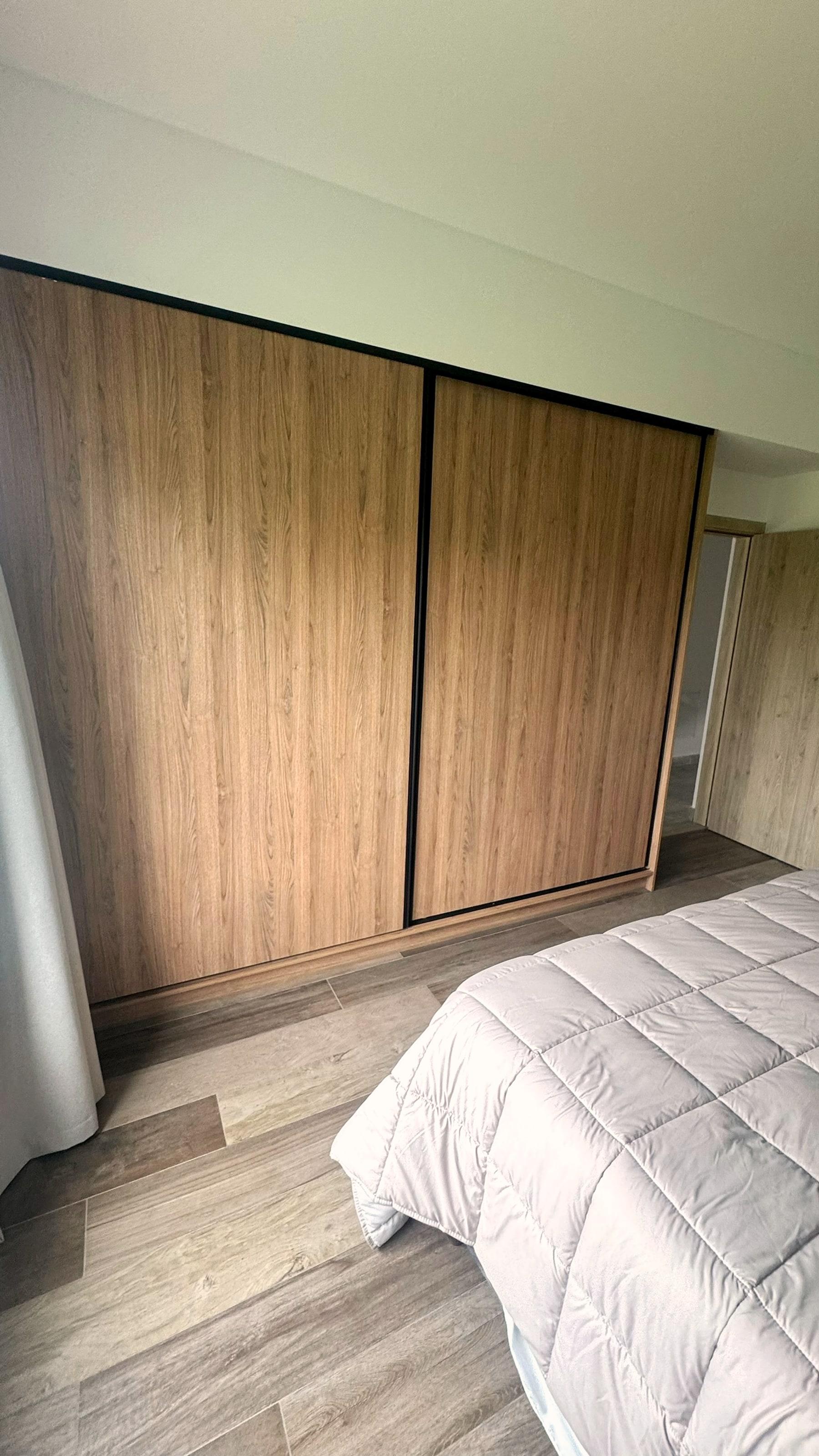 Placard con puertas corredizas de madera y perfil negro