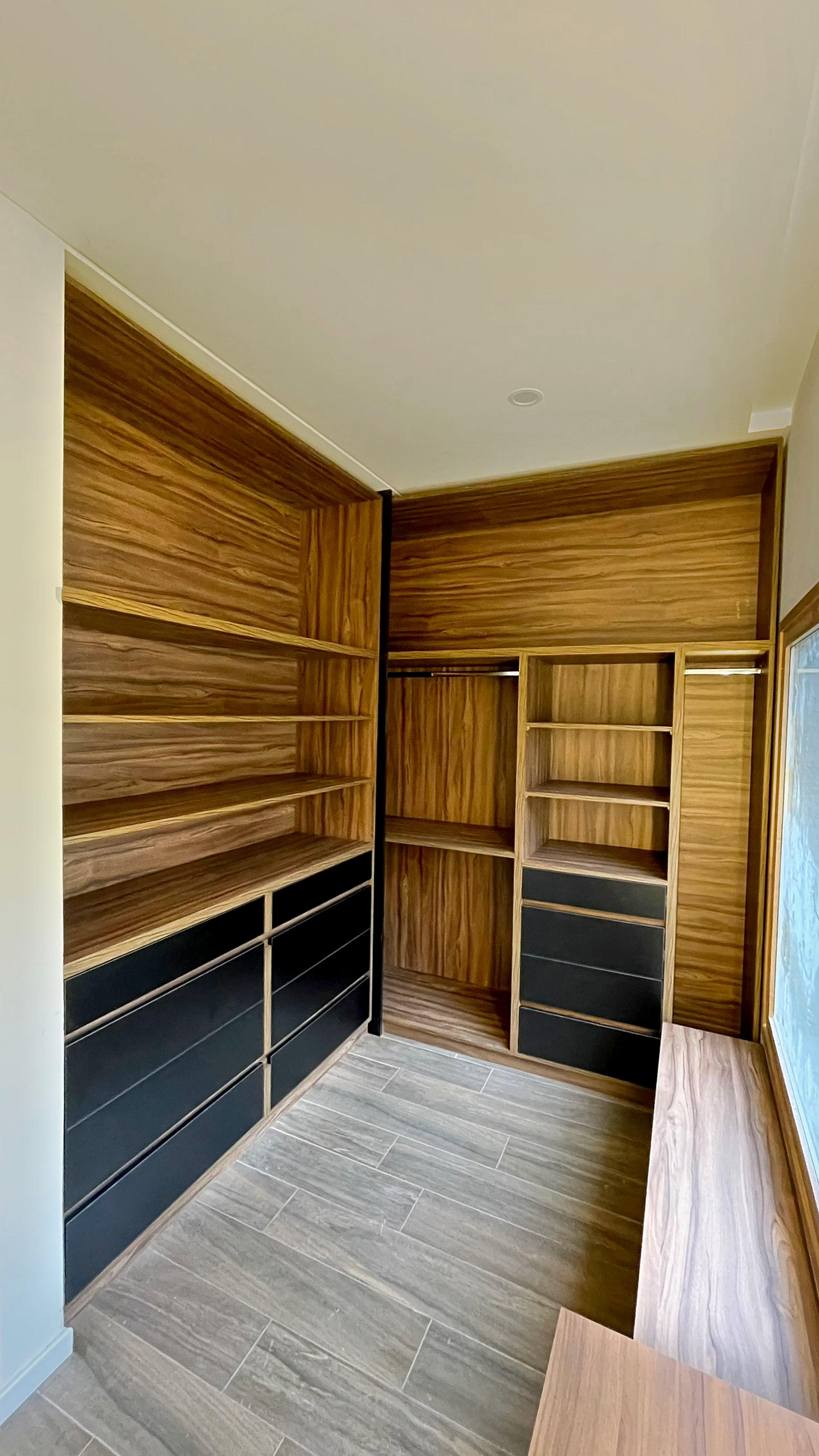 Vestidor en L en madera, con cajones negros, estantes y barrales